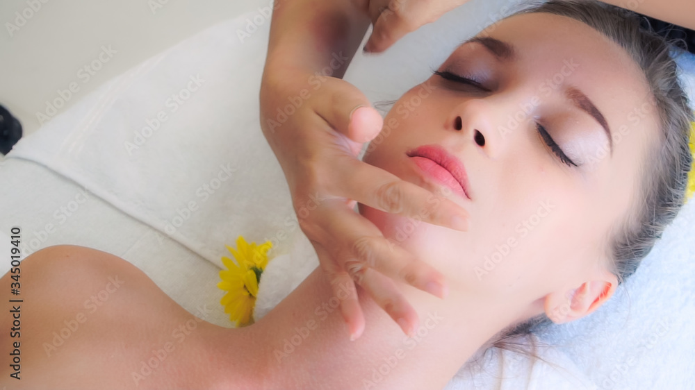 Relaxed woman lying on spa bed for facial and head massage spa treatment by massage therapist in a l