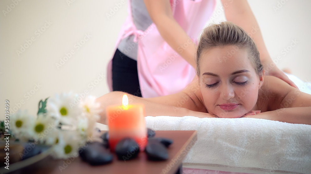 Relaxed woman getting back massage in luxury spa with professional massage therapist. Wellness, heal