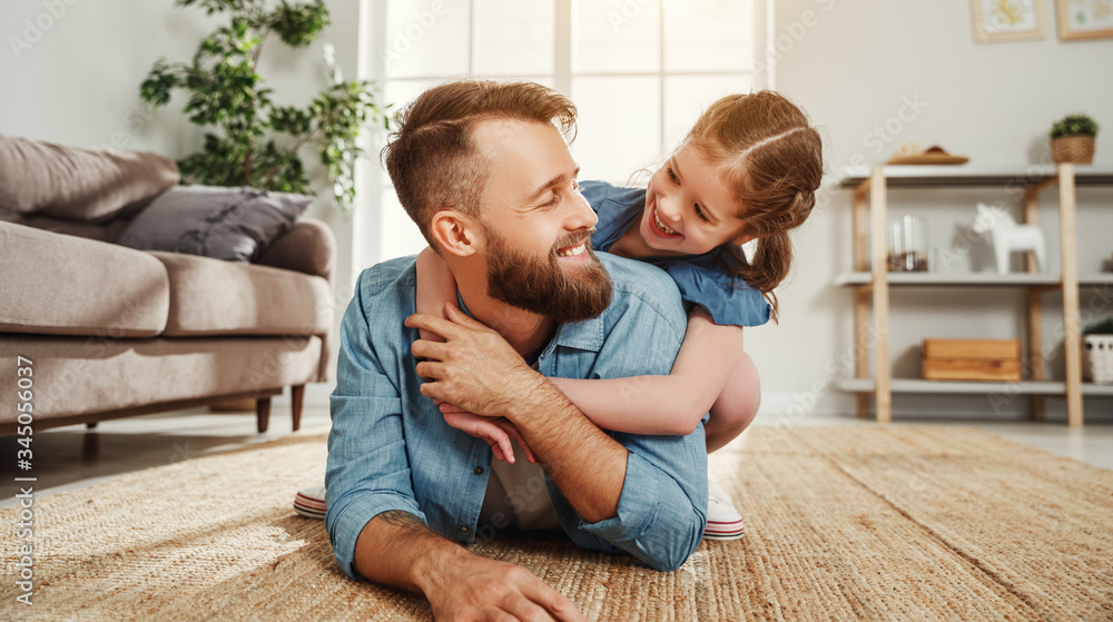 Cheerful father and daughter having fun and hugging in living room.