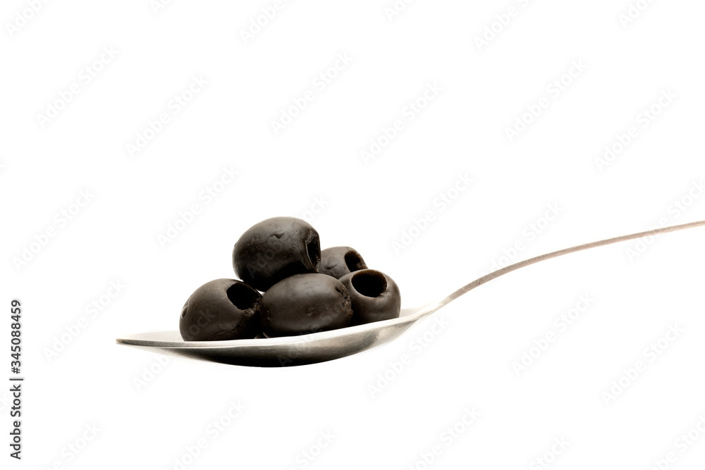 Spoon with black olives on a white background.