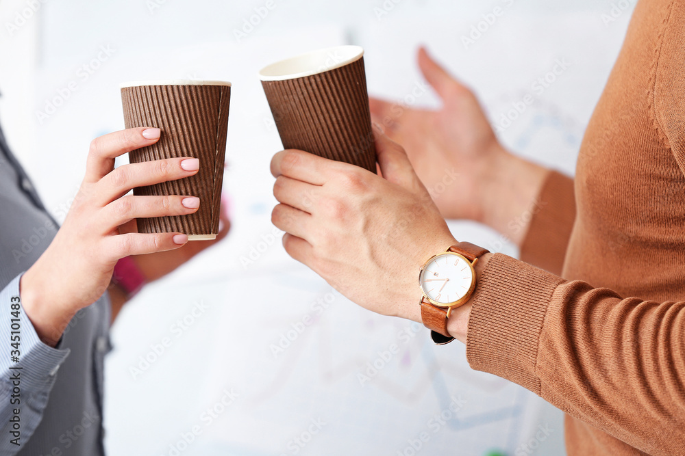 Young colleagues drinking coffee in office, closeup