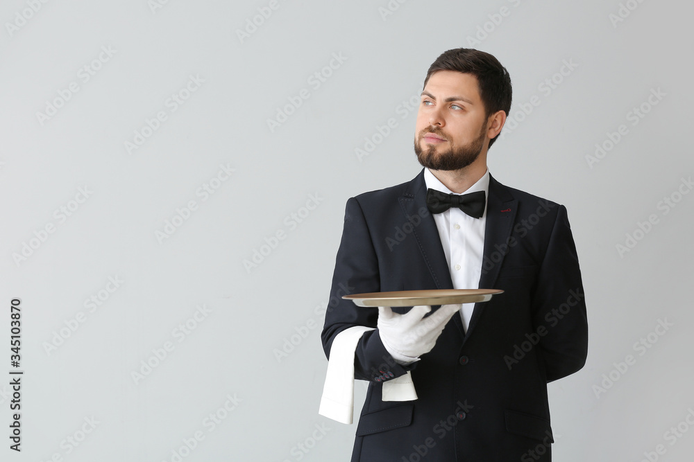 Handsome male waiter on grey background