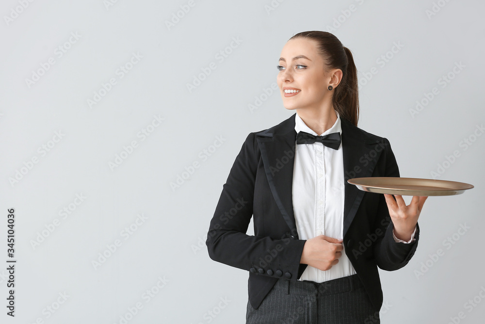 Female waiter with empty tray on grey background