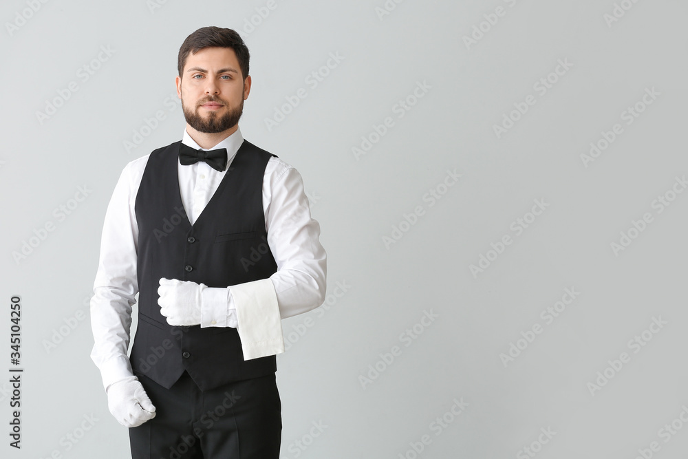 Handsome male waiter on grey background