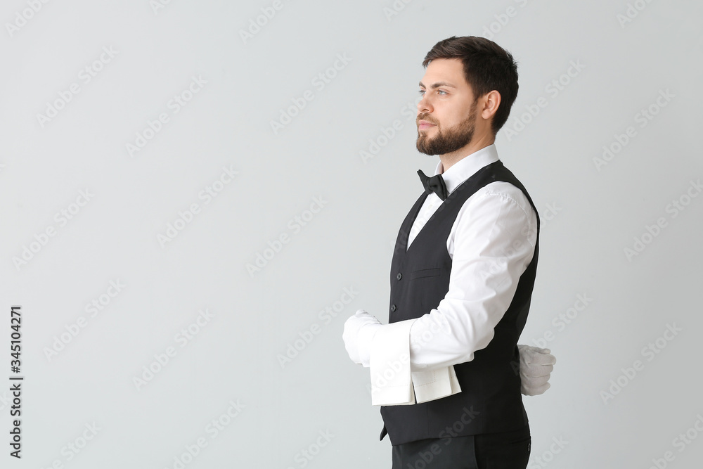 Handsome male waiter on grey background