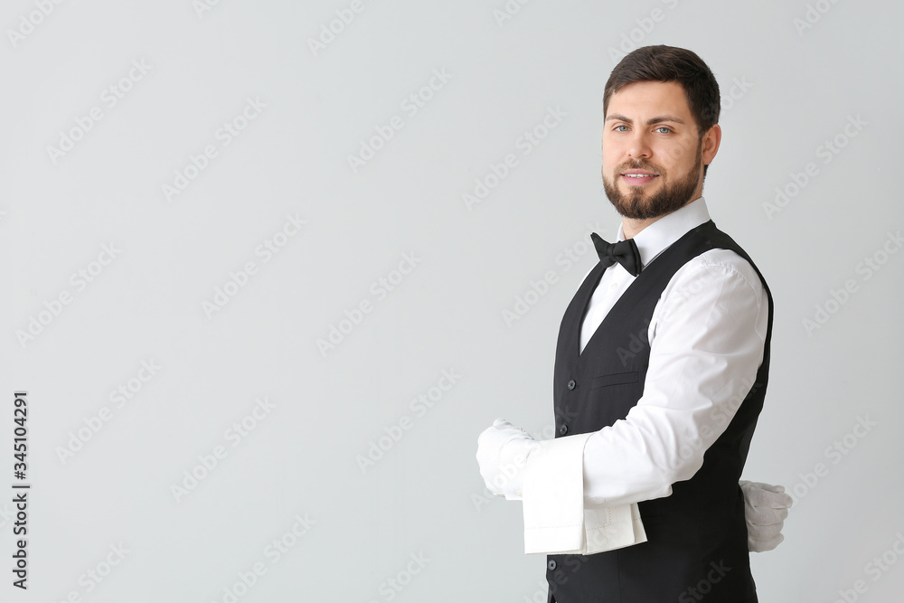 Handsome male waiter on grey background