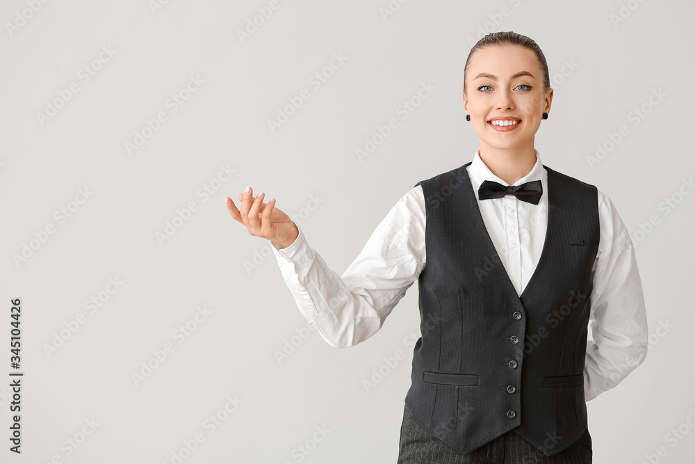 Beautiful female waiter on grey background