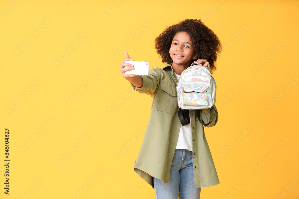 African-American teenage fashion blogger with mobile phone on color background