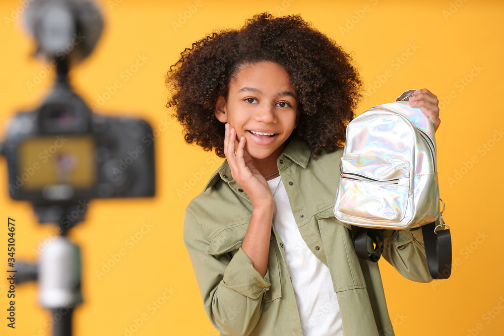 African-American teenage fashion blogger recording video on color background