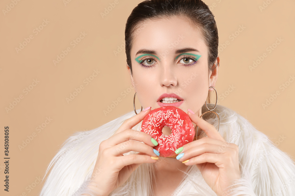 Young woman with beautiful manicure and donut on color background