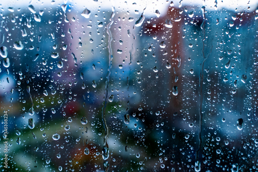 玻璃上的自然水滴。选择性聚焦。雨天城市背景