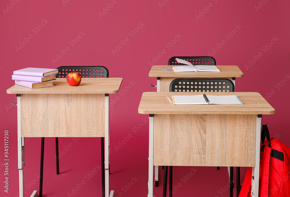 Modern school desks on color background