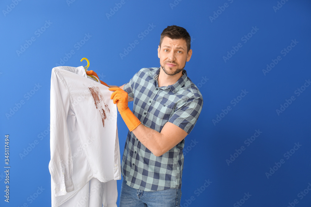 Displeased man with dirty clothes on color background