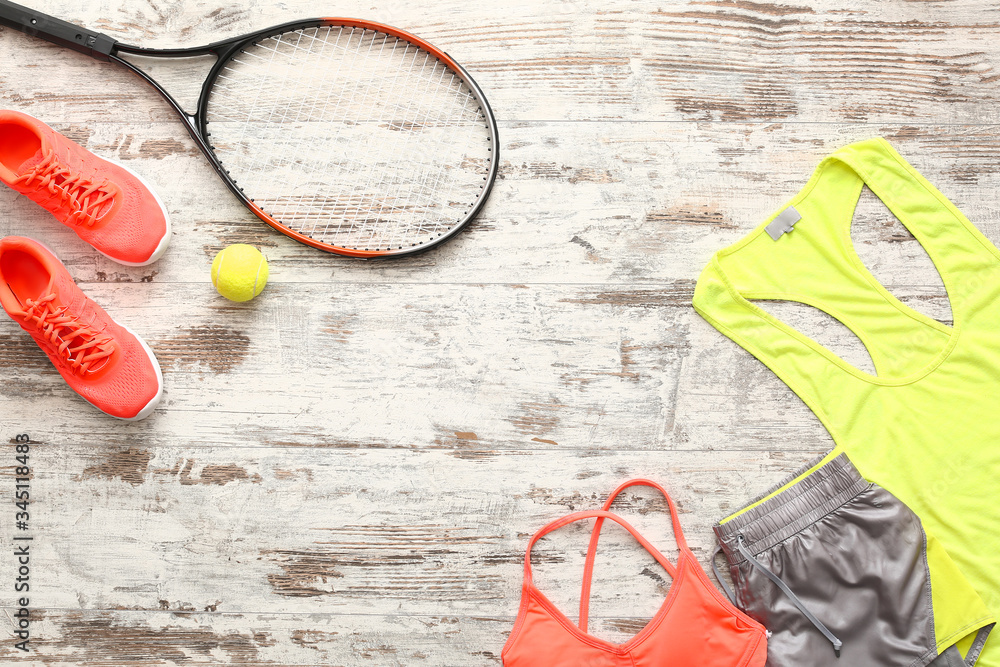 Sportswear and tennis racket on wooden background