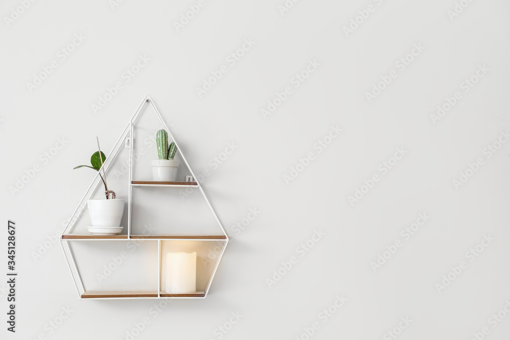 Stylish shelf with decor hanging on wall in room