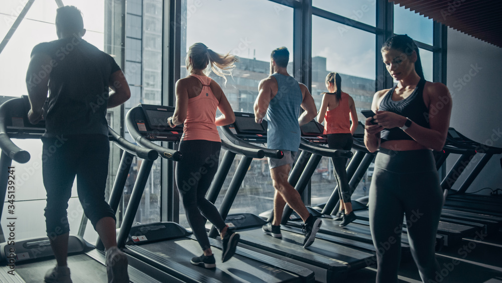 Beautiful Athletic Woman Uses Smartphone Walks Through Fitness Club Gym. Using Social Media, Posting