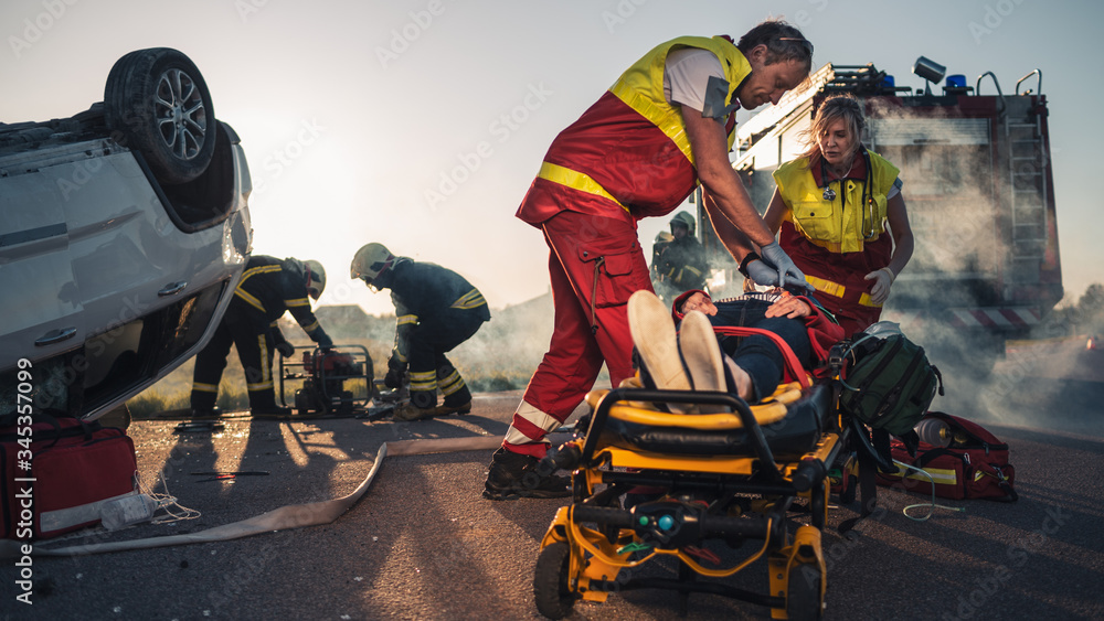 On the Car Crash Traffic Accident Scene: Paramedics Saving Life of a Female Victim who is Lying on S