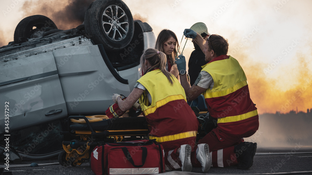 On the Car Crash Traffic Accident Scene: Paramedics Perform First Aid of a Female Victim who is Sitt