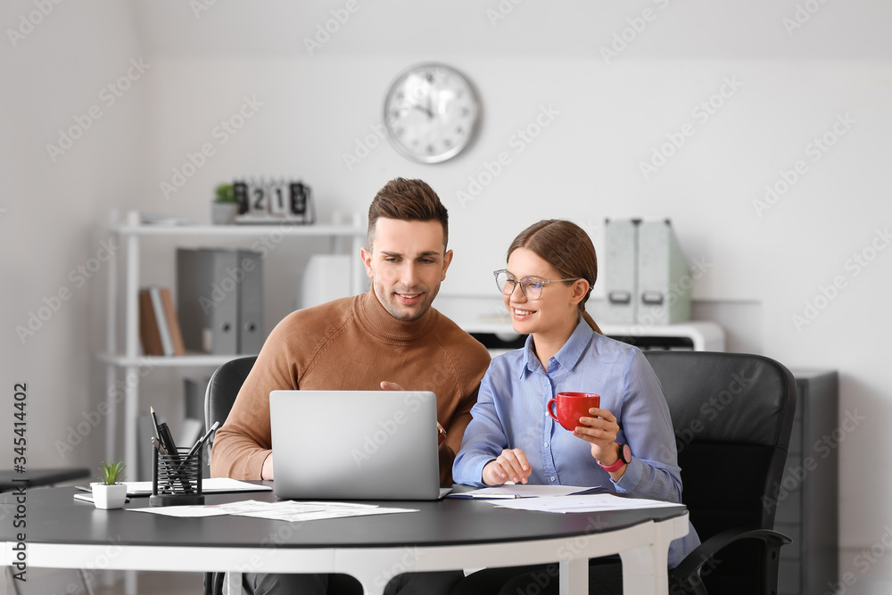 Young colleagues drinking coffee while working in office