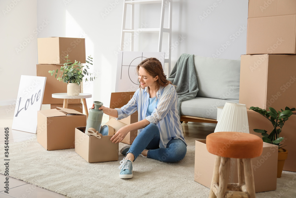 Young woman unpacking moving boxes in her new home