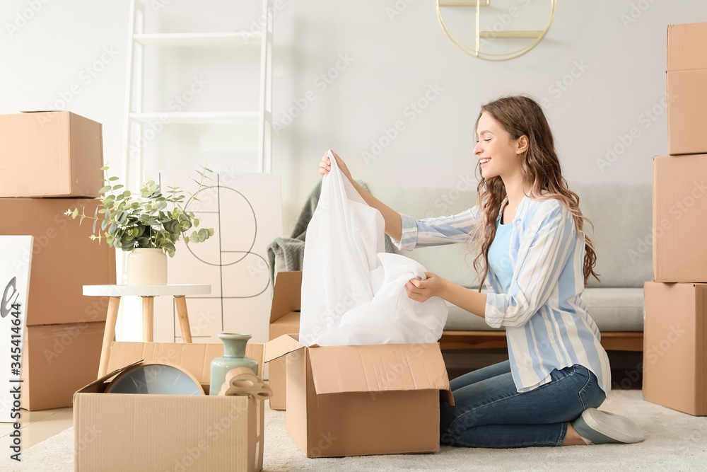 Young woman unpacking moving boxes in her new home