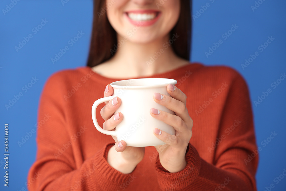 Beautiful young woman with cup of hot cocoa on color background, closeup