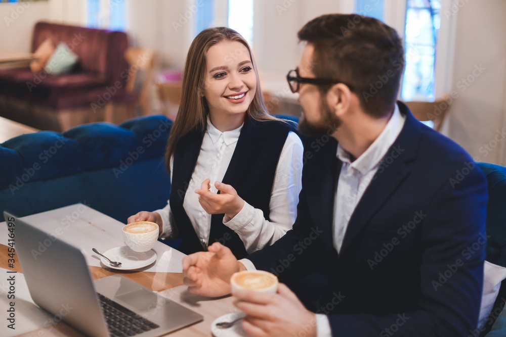 Young business people drinking coffee during work in cafe