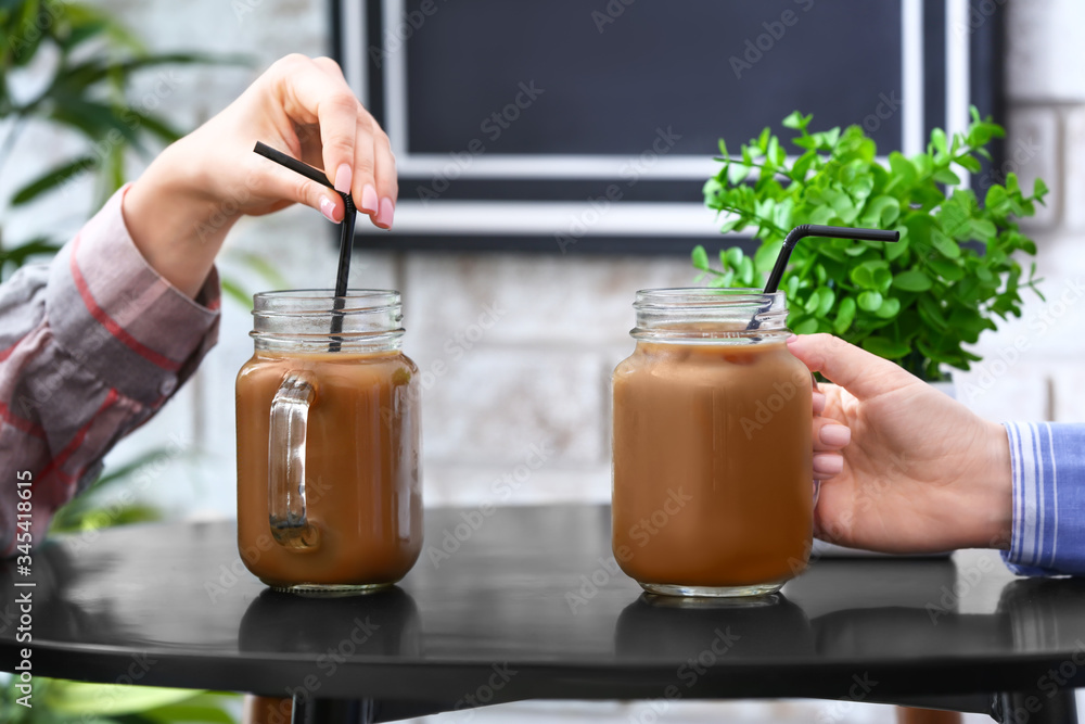 Women with mason jars of tasty iced coffee in cafe, closeup