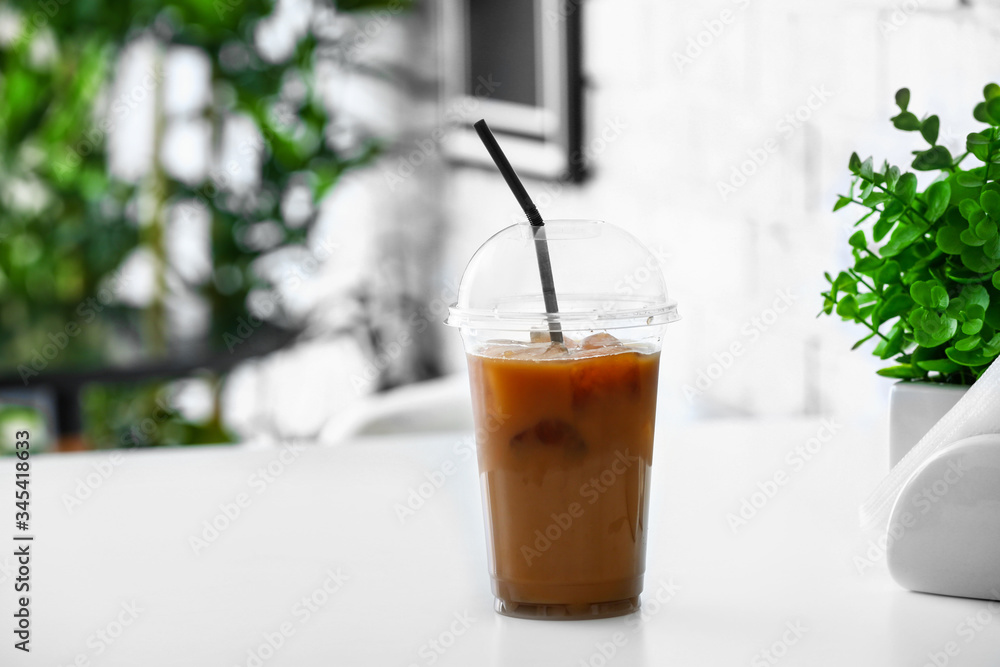 Cup of tasty iced coffee on table in cafe