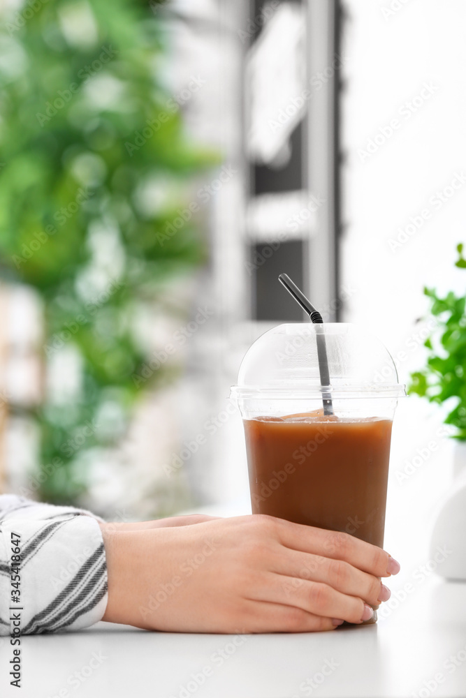 Woman with cup of tasty iced coffee in cafe