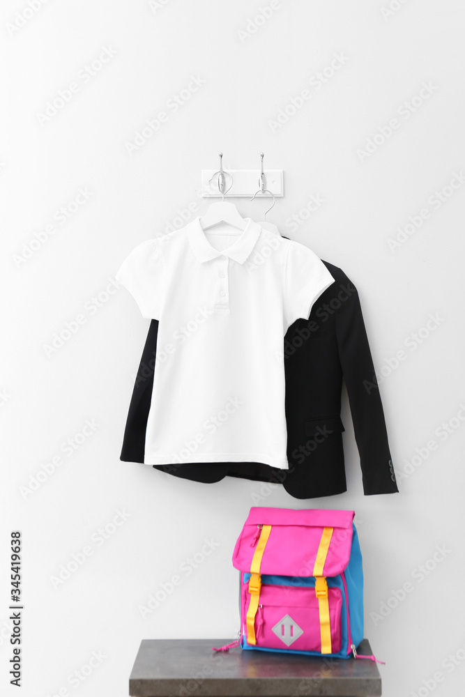 Stylish school uniform with backpack in room