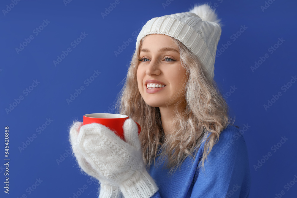 Beautiful young woman with cup of hot chocolate on color background