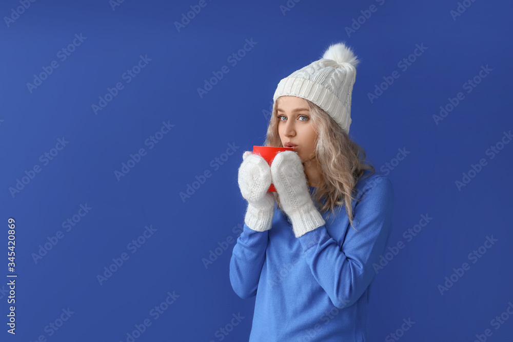 Beautiful young woman with cup of hot chocolate on color background