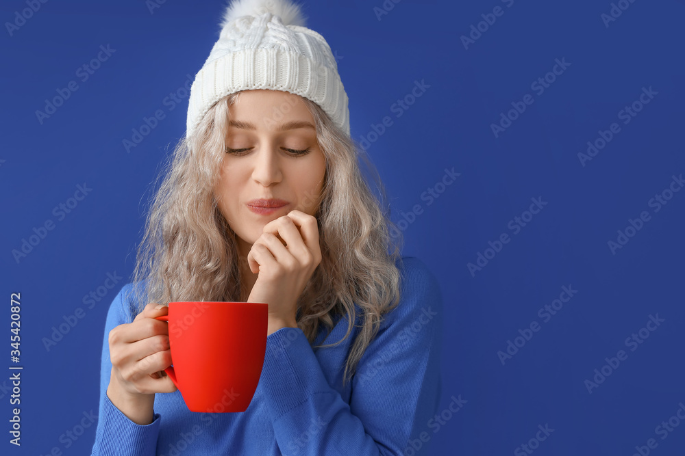 Beautiful young woman with cup of hot chocolate on color background