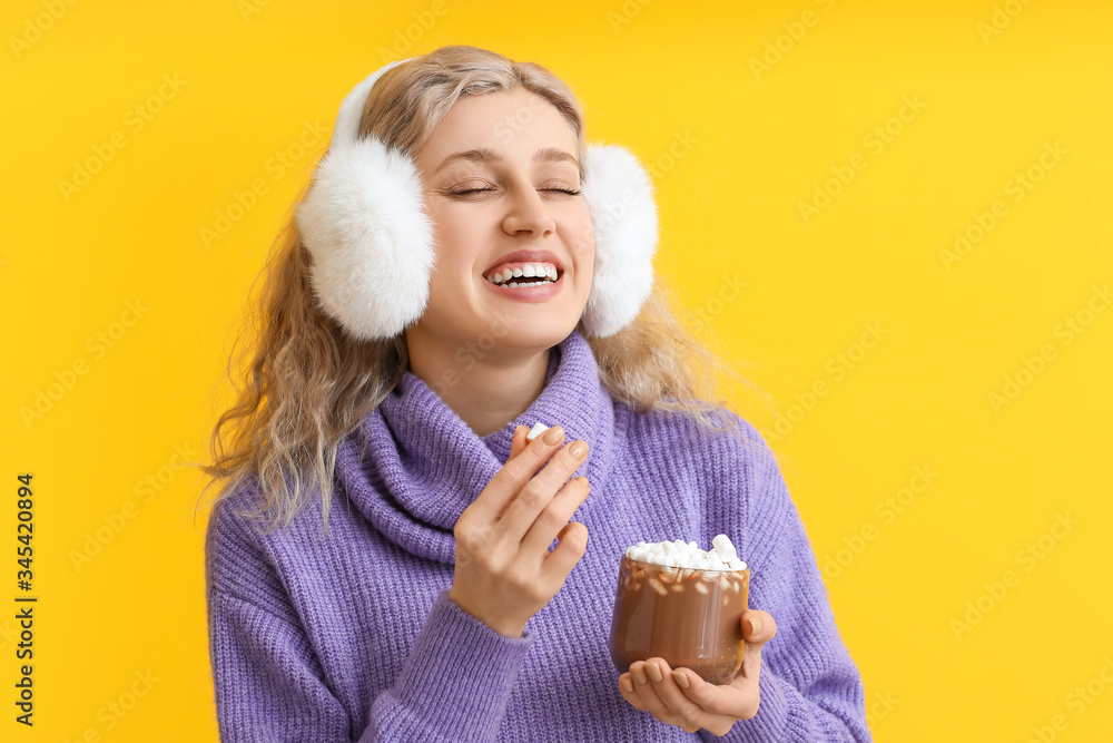 Beautiful young woman with cup of hot chocolate on color background