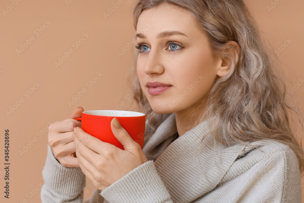 Beautiful young woman with cup of hot chocolate on color background