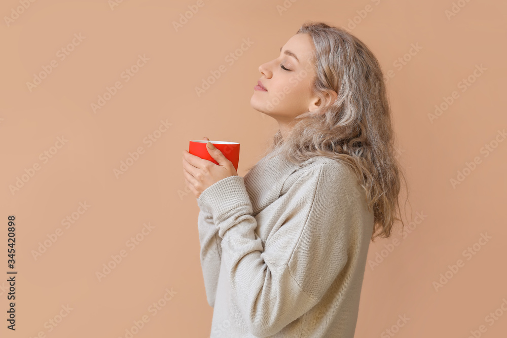 Beautiful young woman with cup of hot chocolate on color background