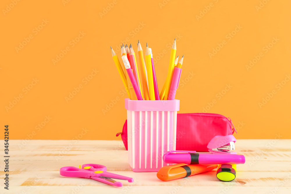 Holder with stationery on table against color background