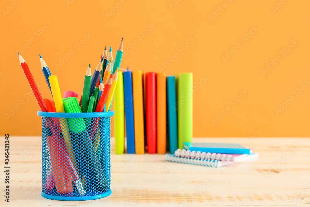 Holder with stationery on table against color background