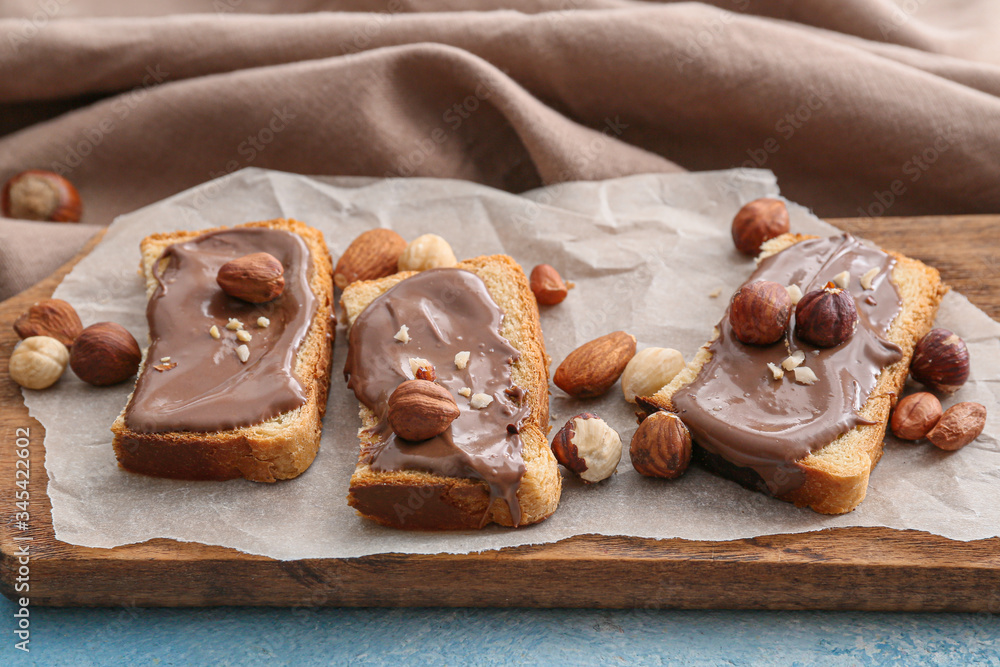 Fresh bread and chocolate paste and nuts on board