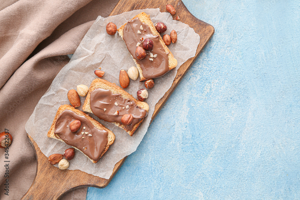 Board with fresh bread and chocolate paste on color background