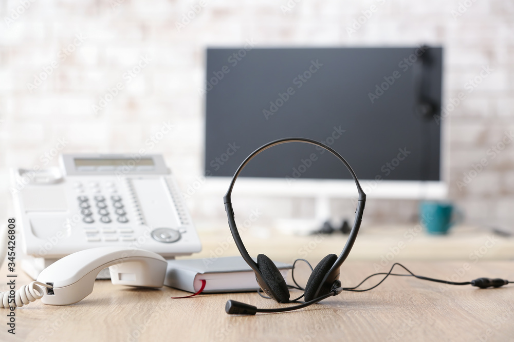 Headset and telephone on table of technical support agent in office