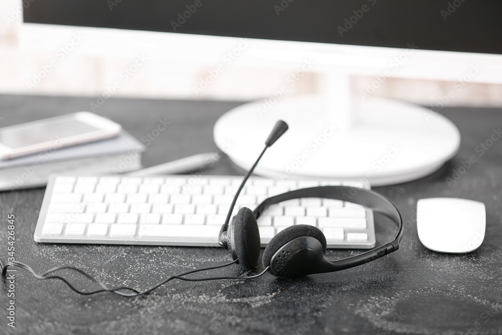 Headset and computer on table of technical support agent in office