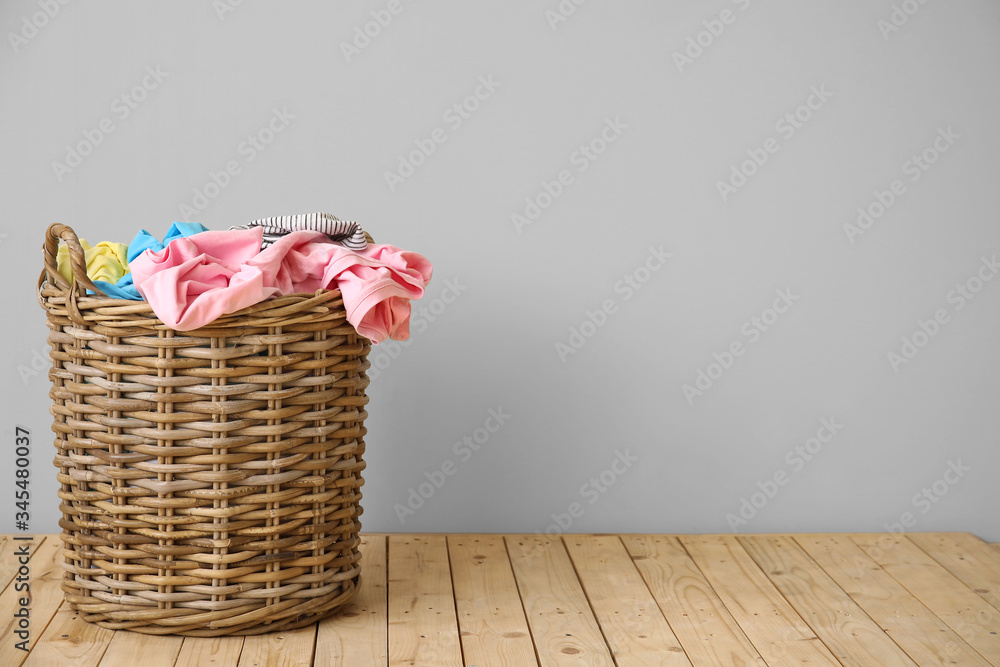 Wicker basket with laundry near light wall