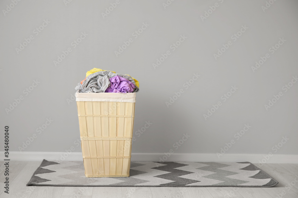 Wicker basket with laundry near light wall