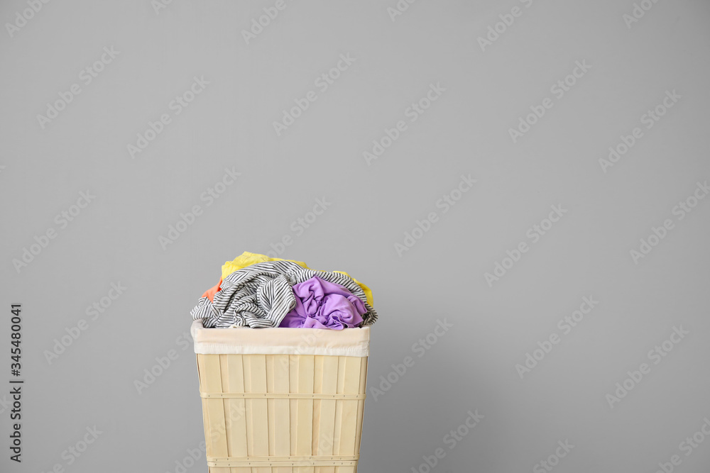 Wicker basket with laundry near light wall