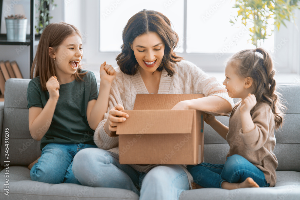 Mother and daughters are unpacking cardboard