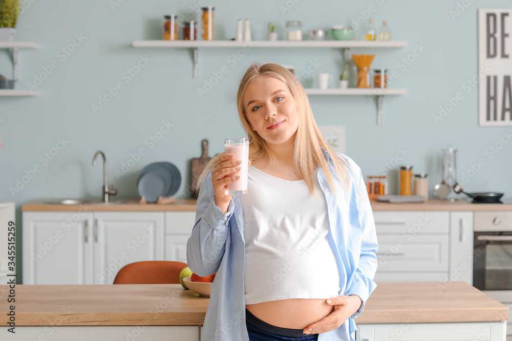 Pregnant woman with healthy yogurt in kitchen