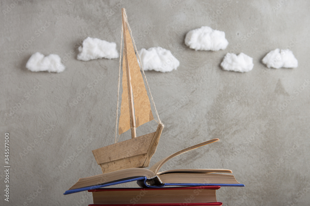 Education is a journey concept, toy boat and books like a sea waves on the wooden table, inspiration