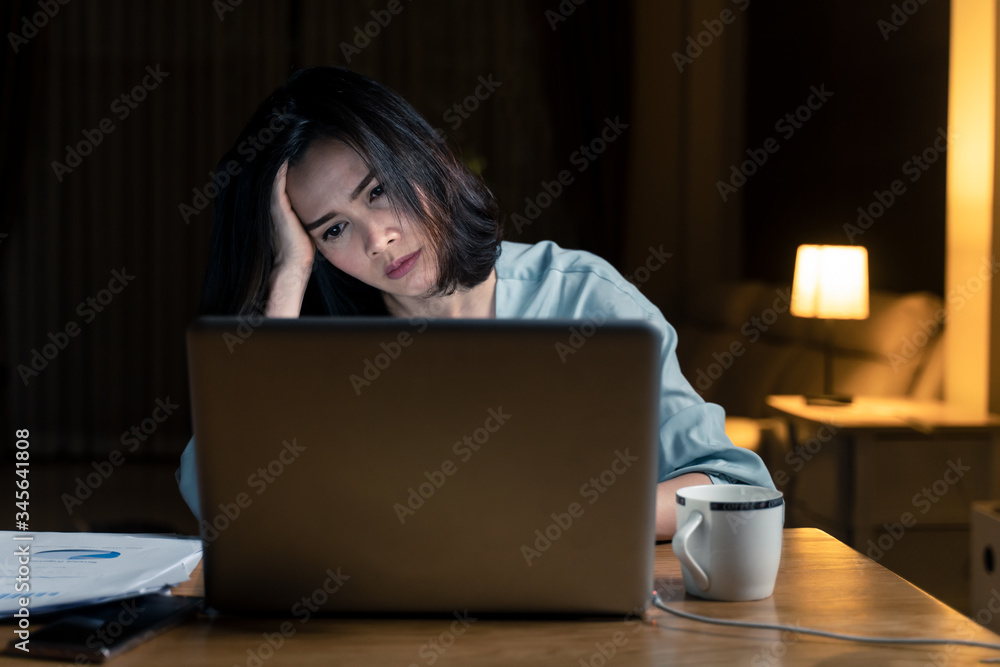 Asian woman work late from home in living room at late night overtime